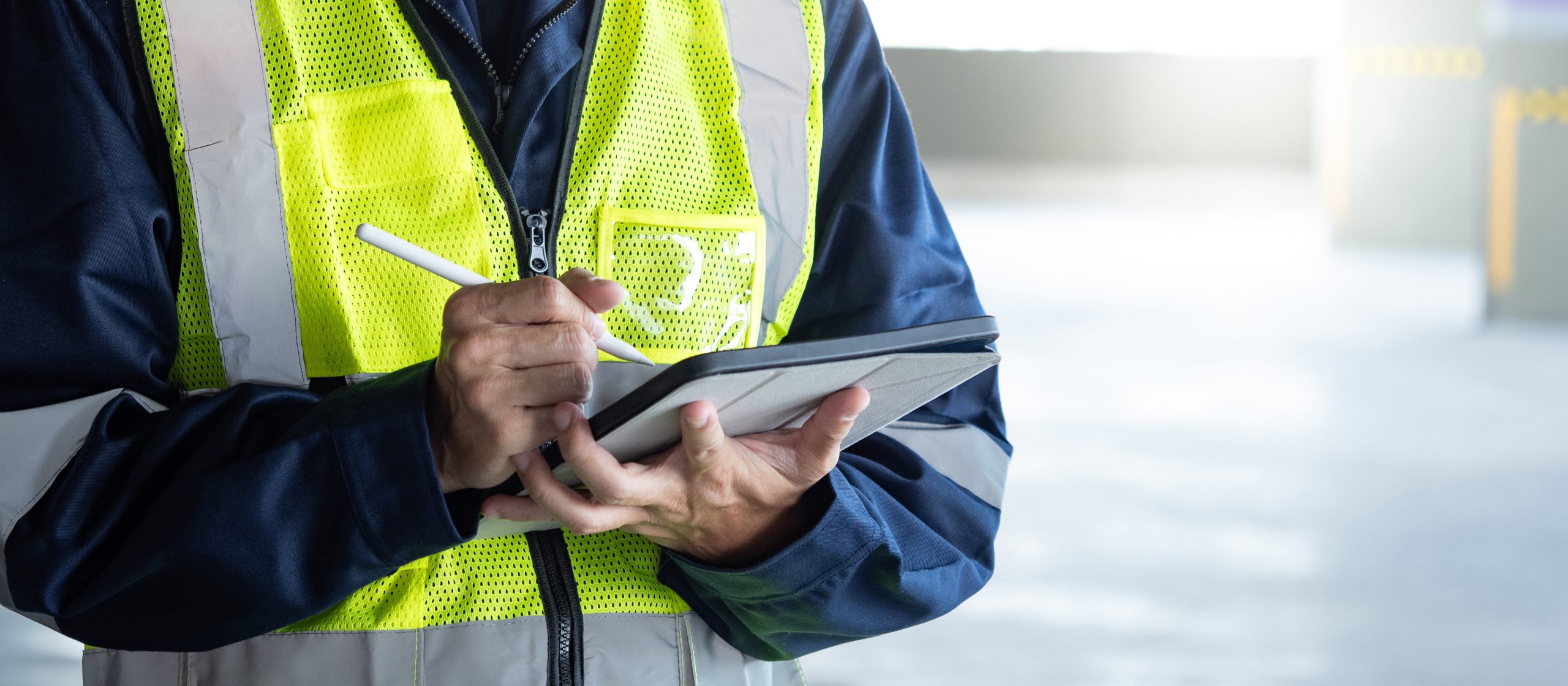 Building inspector man using digital tablet checking safety and security system in the building. Asian male worker in reflective vest working for building maintenance inspection